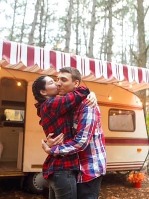 a couple hugging outside their travel trailer after downsizing for RV life